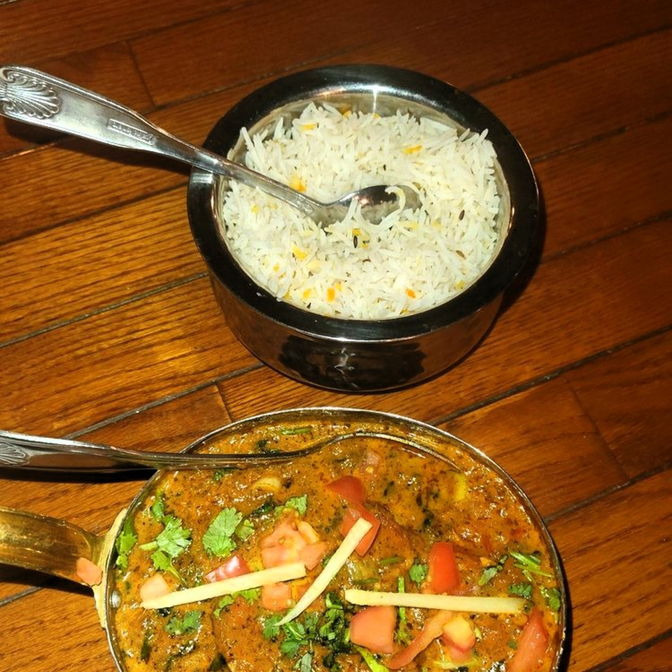 Amber Indian Restaurant's chicken curry with tomatoes and cilantro, alongside a bowl of basmati rice.